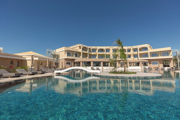 Un hotel con piscina, un puente y una palmera.