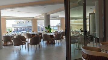 Un comedor amplio con varias mesas y sillas, ventanas grandes y vistas al exterior.
