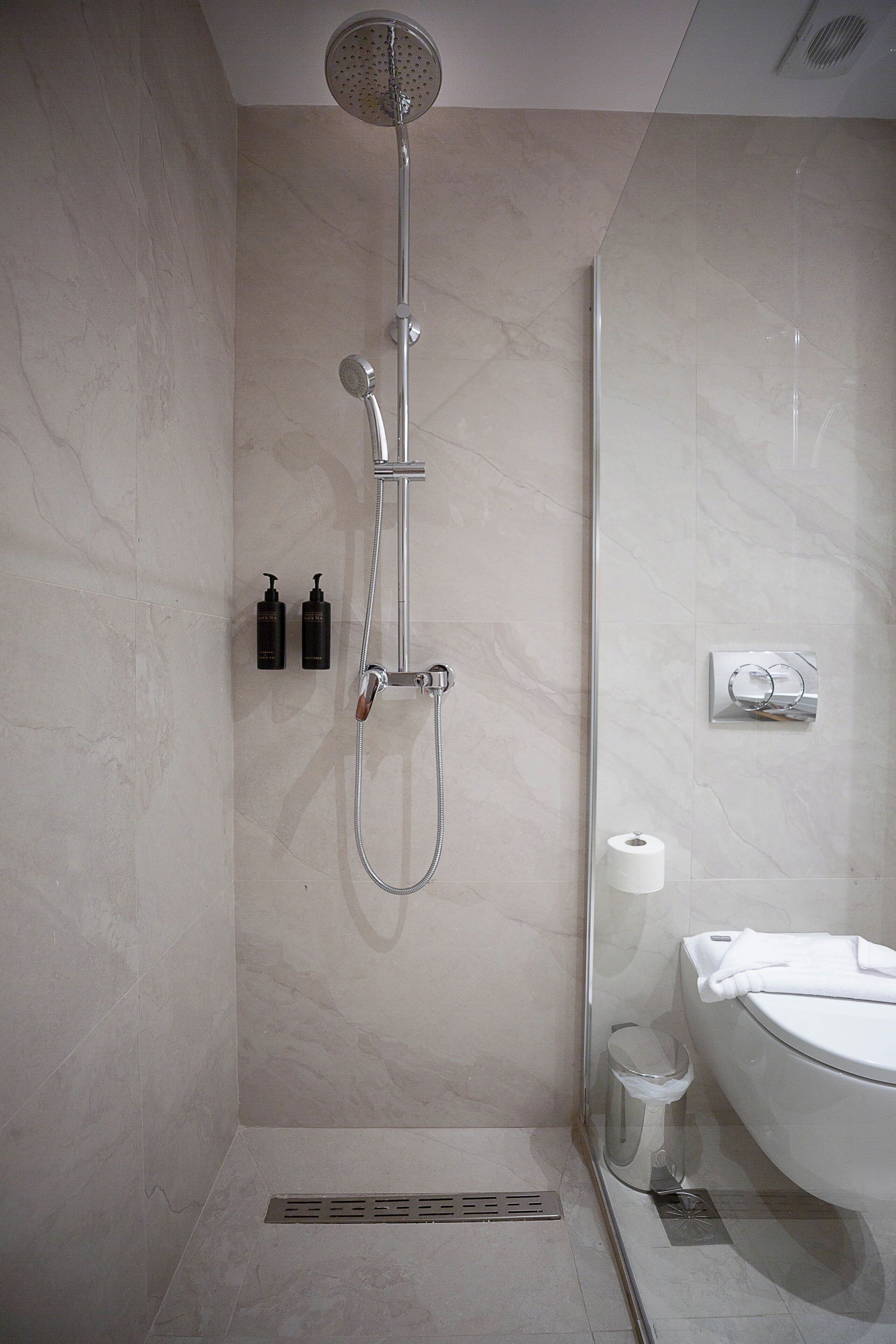 Un baño moderno con ducha, inodoro y lavamanos con mampara de vidrio.