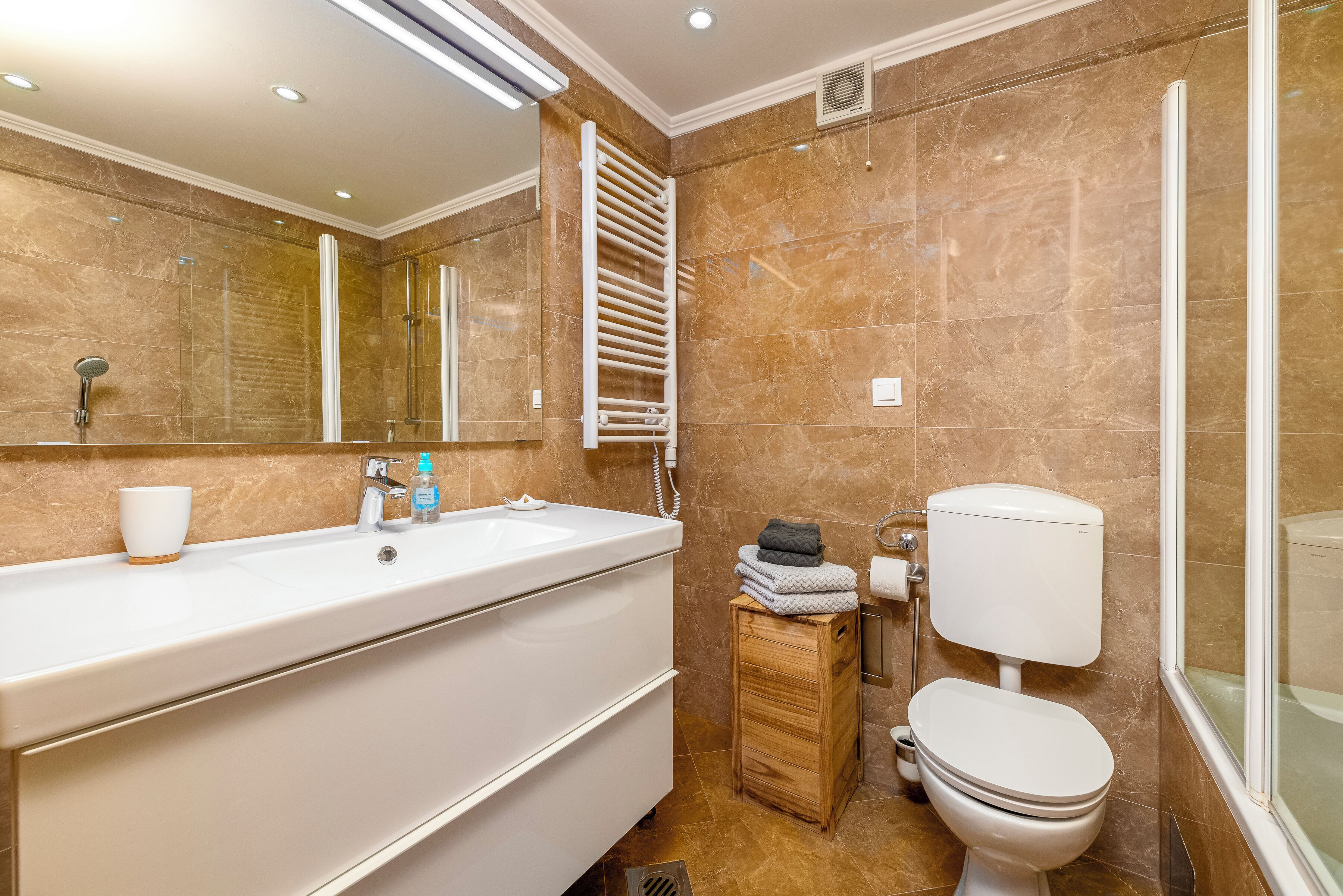 A modern bathroom with a large sink, mirror, towel rack, toilet, and shower area.
