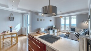 A modern kitchen with a central island, built-in appliances, and a dining area with a table and chairs.