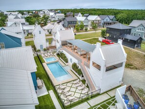 Ein Wohngebiet mit modernen Häusern, einem Swimmingpool und einer Terrasse mit Liegestühlen.