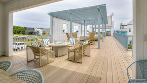En utomhusveranda med möbler i rotting, en pergola och utsikt över det omgivande området.