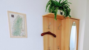 A wooden wardrobe with a mirror, a coat rack, and a shelf with books and a glass.