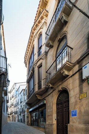 Une rue bordée de bâtiments historiques, dont un bâtiment portant une enseigne indiquant « Francesco Calvo, architecte » et un logo AT bleu.