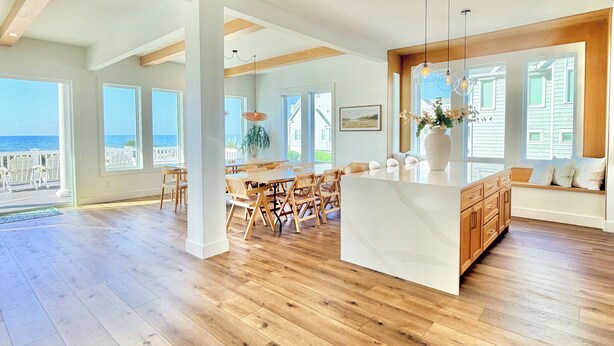 A spacious kitchen with wooden flooring, large windows, and a view of the ocean.