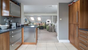Eine moderne Küche mit einer zentralen Kochinsel, Holzschränken und einem Essbereich mit einem grünen Sofa und Tisch.