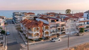 A multi-story hotel with balconies, a central courtyard, and a view of the sea. - Zeus Luxury Suite in Nea Flogita (Flogita)