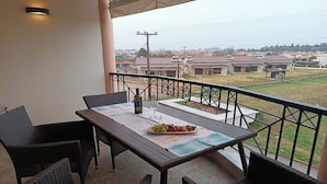A balcony with a table set for two, a bottle of wine, and a fruit plate. - Zeus Luxury Suite in Nea Flogita (Flogita)