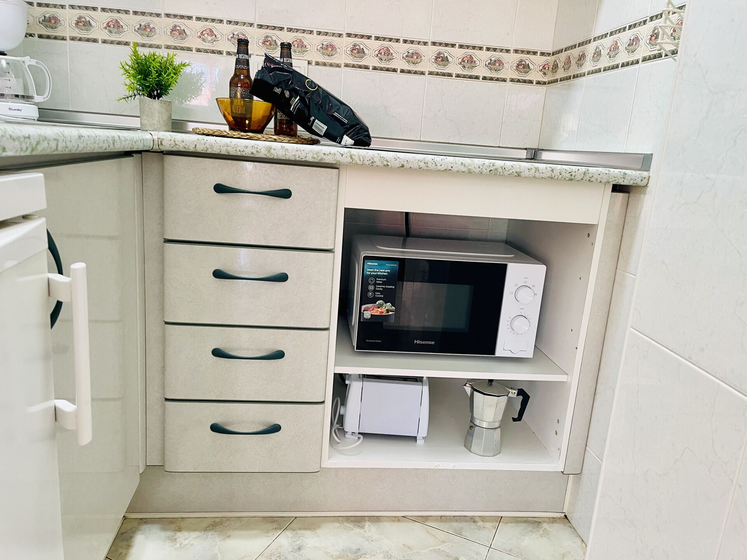 A kitchen with a microwave, a coffee maker, and a cabinet with drawers.