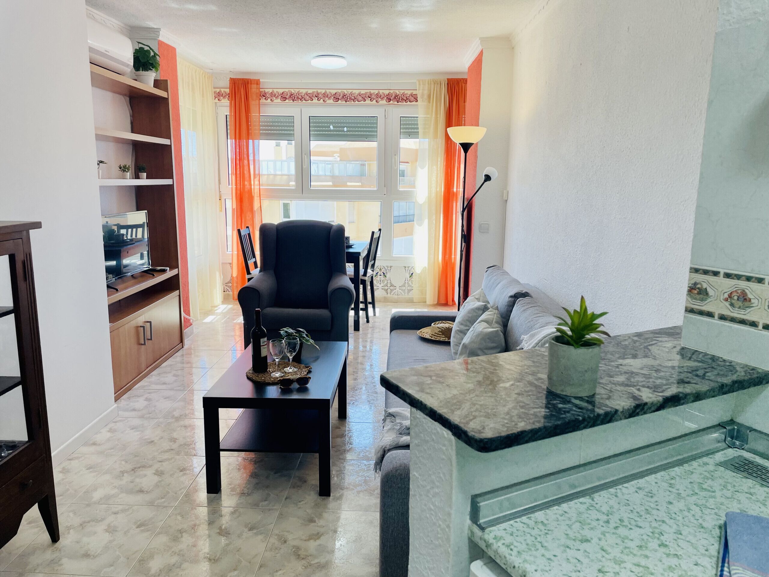 A living room with a sofa, armchair, coffee table, and a dining area with chairs and a table.