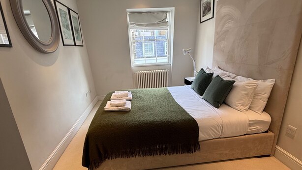 A bedroom with a bed, a window, a radiator, and a nightstand. - Pavilion Road Mews House - 4 bed (London)