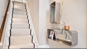 A staircase with a wooden handrail and beige carpeted steps. - Pavilion Road Mews House - 4 bed (London)