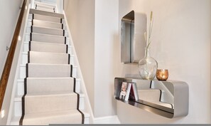 A staircase with a wooden handrail and beige carpeted steps. - Pavilion Road Mews House - 4 bed (London)