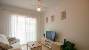 A living room with a sofa, a TV on a stand, a ceiling fan, and a plant. - Andaluc a Sun Duplex Torrox-costa (Torrox)
