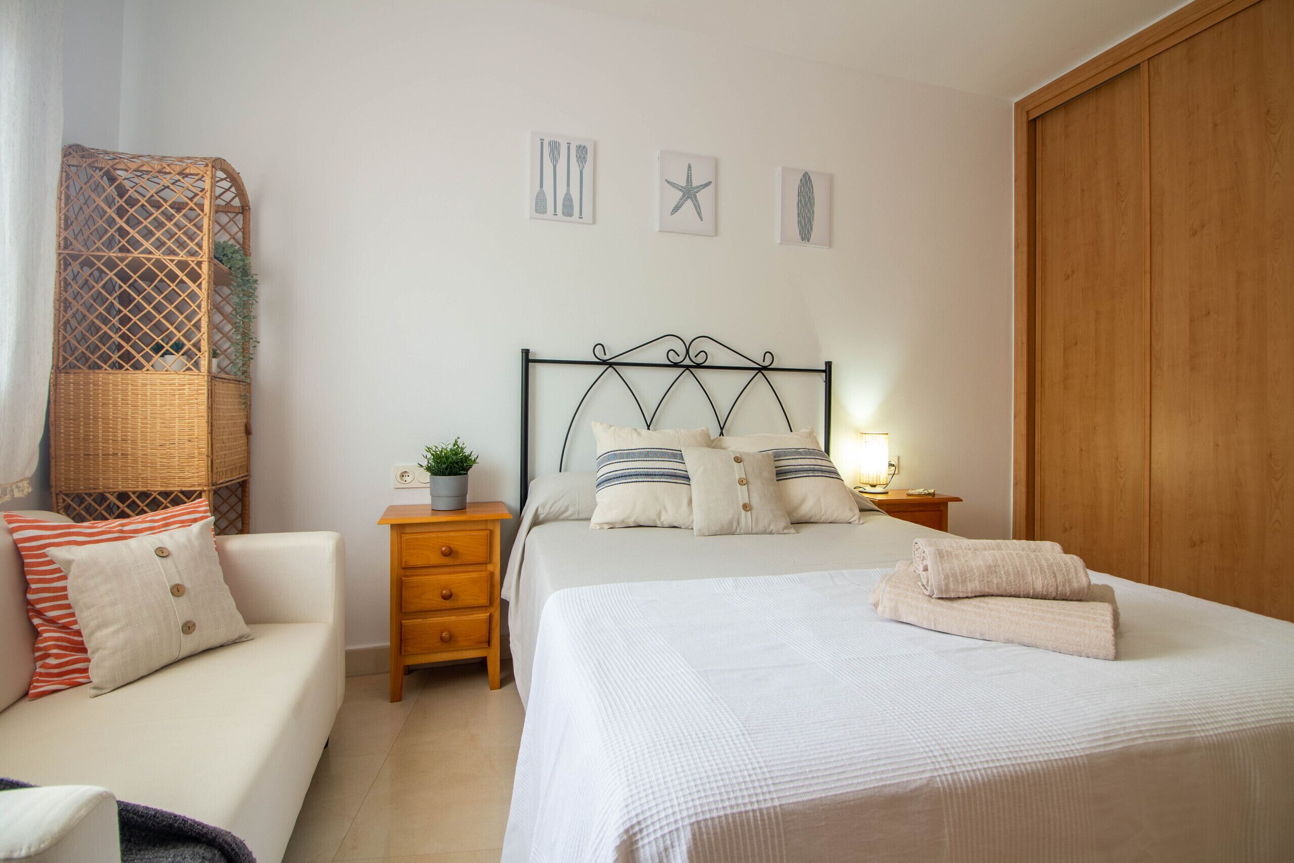 Une chambre à coucher comprenant un lit, des tables de chevet, une commode, une armoire en bois et des œuvres d’art murales.