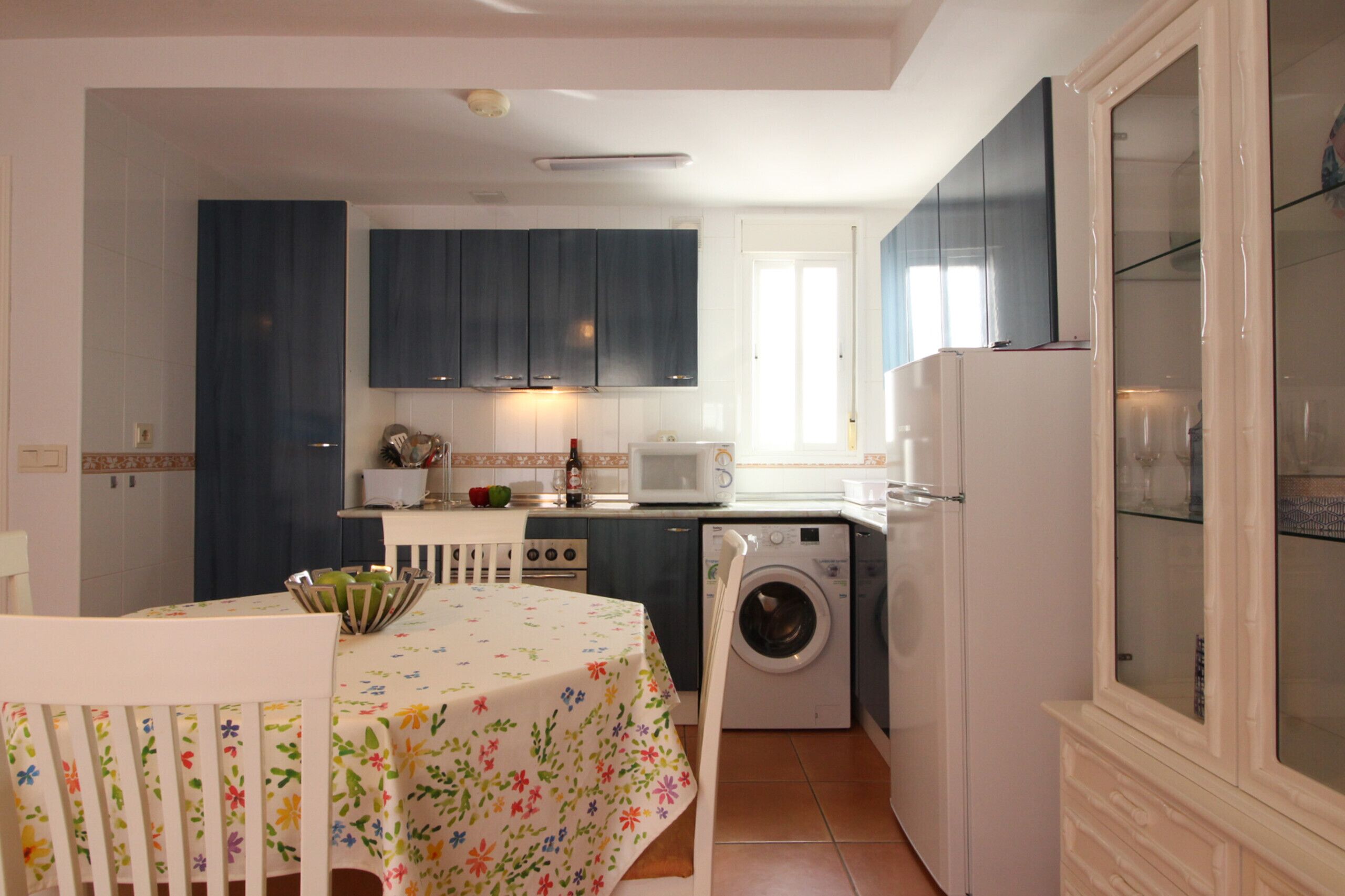Una cocina compacta con lavadora, microondas y comedor con mesa y sillas.