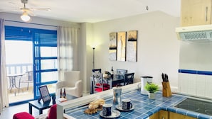 A modern kitchen with a blue-tiled countertop, a built-in stove, and a dining area with a table and chairs. - Edificio Arrecife Primera L nea Vistas al Mar y (Torrox)