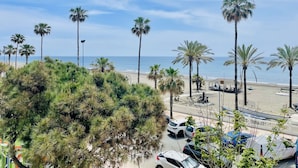 A beach with palm trees, parked cars, and a clear sky. - Edificio Arrecife Primera L nea Vistas al Mar y (Torrox)