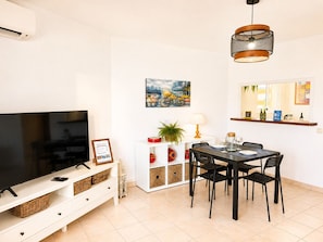 A modern living room with a flat-screen TV, dining table with chairs, a hanging light fixture, and a painting on the wall. - Madrid 401 by At Home Costa del Sol (Torrox)