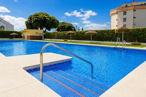 A swimming pool with a metal ladder, clear blue water, and a hedge-lined border. - Madrid 401 by At Home Costa del Sol (Torrox)