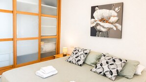 Hotelkamer met een bed, nachtkastje, lamp en groot raam met geëtste glaspanelen.