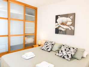 A hotel room with a bed, a nightstand, a lamp, and a large window with frosted glass panels. - Madrid 401 by At Home Costa del Sol (Torrox)