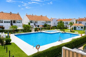 A swimming pool surrounded by white buildings with red-tiled roofs, a clear sky, and well-maintained greenery. - Madrid 401 by At Home Costa del Sol (Torrox)