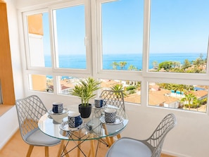 Ein Balkon mit Glastisch, Stühlen und einem Blumentopf.