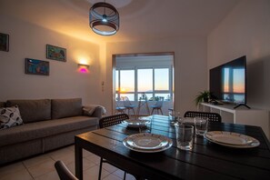 A dining area with a table set for two, a sofa, and a TV on a stand. - Madrid 401 by At Home Costa del Sol (Torrox)