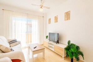 A living room with a sofa, a coffee table, a TV on a stand, a ceiling fan, and a plant. - Andalusia Sun Duplex | Torrox-Costa (Torrox)