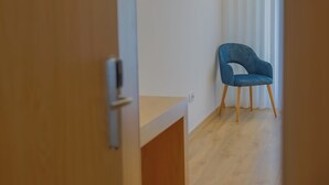 Una habitación con suelo de madera, una silla azul y una puerta con manija.