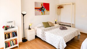 Een slaapkamer met een bed, bedlampjes, een boekenkast, een spiegel en een kunstwerk aan de muur.