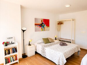 A bedroom with a bed, bedside lamps, a bookshelf, a mirror, and a wall art piece. - Madrid 810 by At Home Costa del Sol (Torrox)