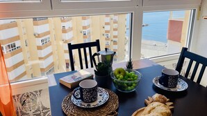 Une table à manger avec un livre, un bol de fruits, deux tasses et une assiette de pain.