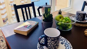 Une table avec un livre, un bol de raisins, une tasse et une plante en pot.
