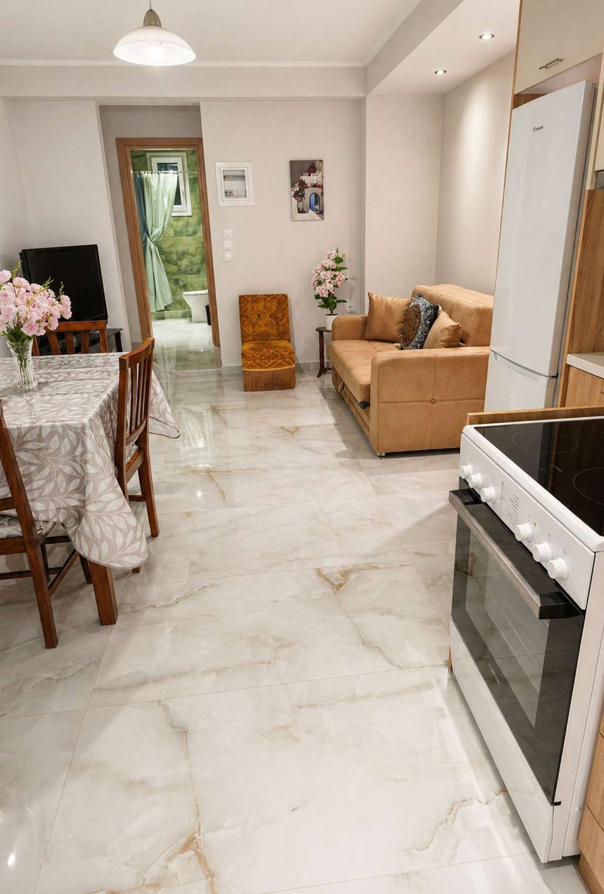 A modern kitchen with a built-in oven, a dining area with a table and chairs, and a living area with a sofa and a small rug.