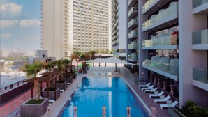 A modern hotel with a rooftop pool, multiple floors, and a cityscape view. - Free Housekeeping Visits During Your Stay - Stayshort - Majestic Studio in Bloom Tower C Perfect for 3 (Dubai)
