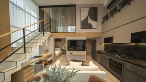 A modern interior with a staircase, a dining area, a living room, and a kitchen.