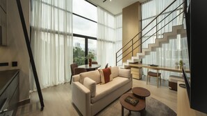 A modern living room with a sofa, coffee table, and a staircase.