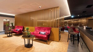 A modern lobby with a reception desk, seating area with sofas and chairs, and a decorative wall. - PLAZA Residence Wiener Neustadt (Wiener Neustadt)