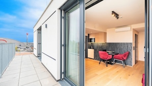 A modern building with a glass door leading to a dining area with two red chairs and a table. - PLAZA Residence Wiener Neustadt (Wiener Neustadt)