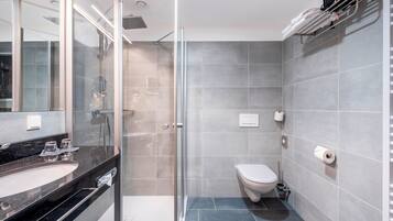 A modern bathroom with a glass shower enclosure, a white toilet, and a black countertop with a sink.