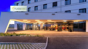 A modern hotel entrance with a glass facade, a sign indicating it's a Plaza Inn, and a visible outdoor seating area. - PLAZA Residence Wiener Neustadt (Wiener Neustadt)