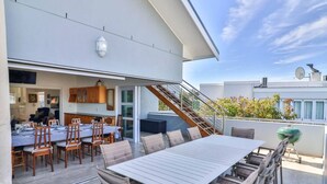 A rooftop patio with a dining table and chairs, a barbecue grill, and a staircase leading to an upper level. - Vonkelwyn | Bright and Breezy by Grotto Beach (Hermanus)