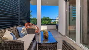 Ein Balkon mit Korbmöbeln, einem Stuhl und einem Tisch mit einer Ananas.