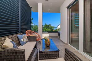 A balcony with wicker furniture, a chair, and a table with a pineapple. - Modern apartment for 4-5 persons with terrace, sea view (Dramalj)