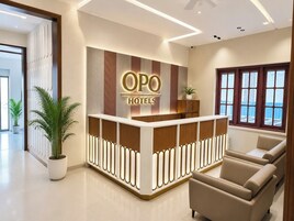 A reception desk with 'OPO HOTELS' signage, a potted plant, and a seating area with sofas.