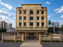 A large, beige building with 'OPO ESSENTIAL NANDNI' signage, featuring a symmetrical facade, large windows, and a central entrance with a gated driveway.