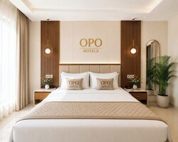 A hotel room with a large bed, two nightstands, a mirror, and a potted plant.
